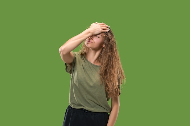 Mujer que tiene dolor de cabeza. Aislado sobre verde.