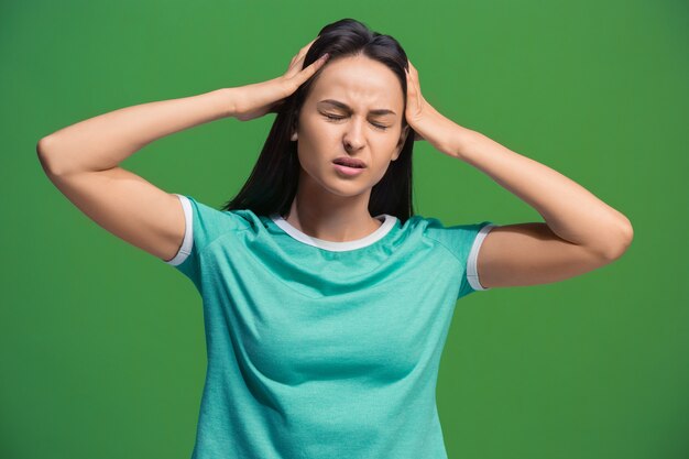 Mujer que tiene dolor de cabeza en verde