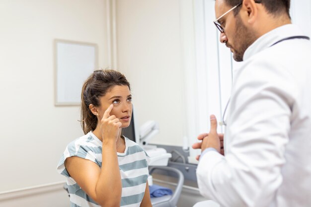 Mujer que tiene un problema en los ojos y dolor Doctor que trabaja en la oficina y escucha al paciente, ella le está explicando sus síntomas concepto de atención médica y asistencia