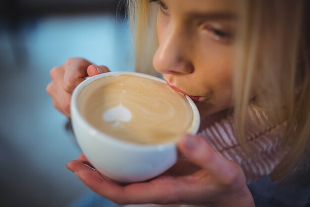 Mujer que tiene una taza de café en la cafetería ©