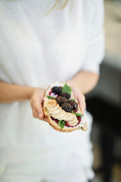 Mujer que tiene una tostada con mermelada de moras y queso crema vegano