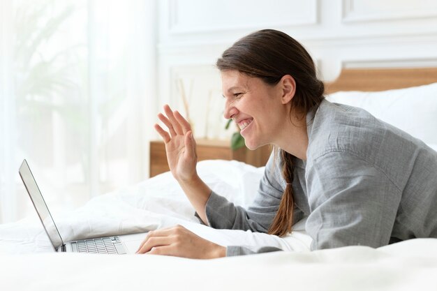 Mujer que tiene una videollamada en la cama