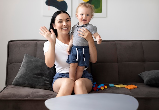 Foto gratuita mujer que tiene una videollamada con su familia mientras sostiene a su bebé