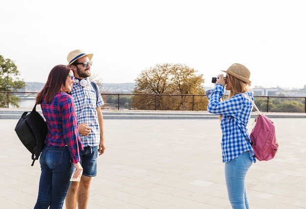 Mujer que toma la foto de la feliz pareja joven en cámara