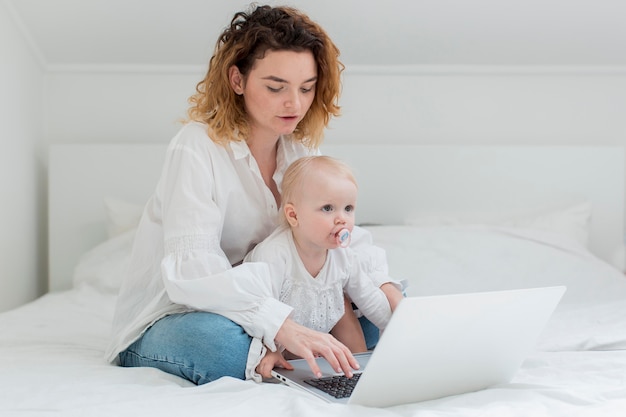 Foto gratuita mujer que trabaja en la cama con niño