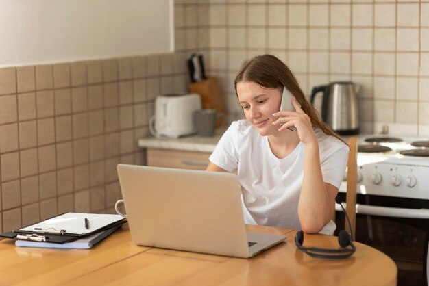 Mujer que trabaja en casa en la cocina durante la cuarentena en la computadora portátil