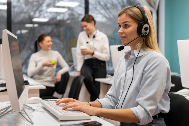 Mujer que trabaja en un centro de llamadas hablando con clientes usando auriculares y micrófono
