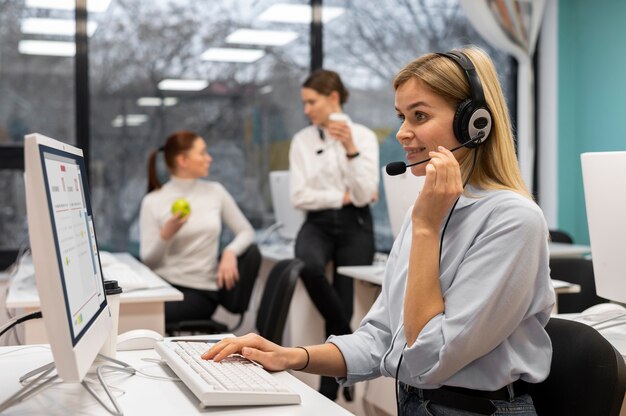 Mujer que trabaja en un centro de llamadas hablando con clientes usando auriculares y micrófono