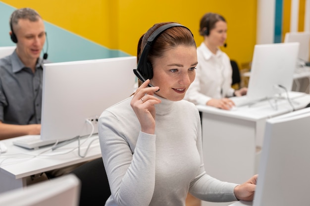 Mujer que trabaja en un centro de llamadas hablando con clientes usando auriculares y micrófono