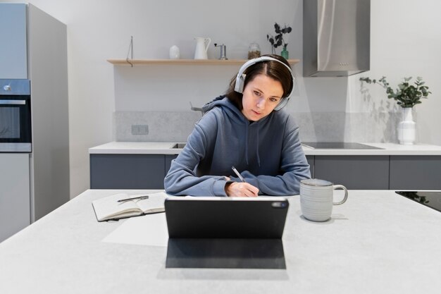 Mujer que trabaja desde la cocina de casa con tableta