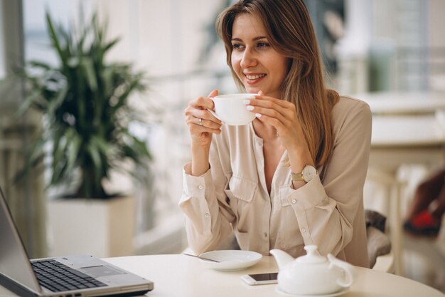 Mujer que trabaja en la computadora portátil y bebiendo té