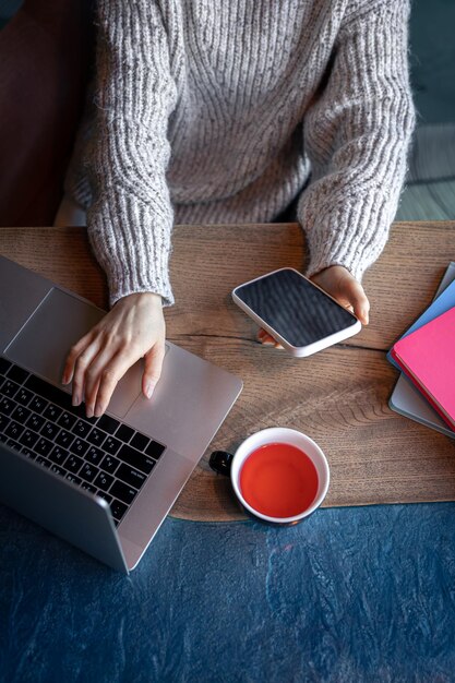 Mujer que trabaja en una computadora portátil en un café con una vista superior de la taza de té