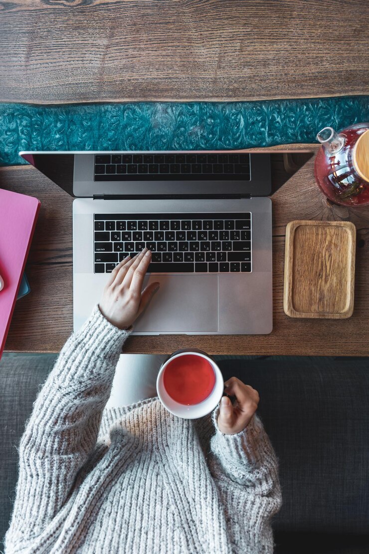 Mujer que trabaja en una computadora portátil en un café con una vista superior de la taza de té