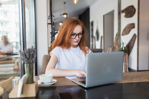 Mujer que trabaja en la computadora portátil en café