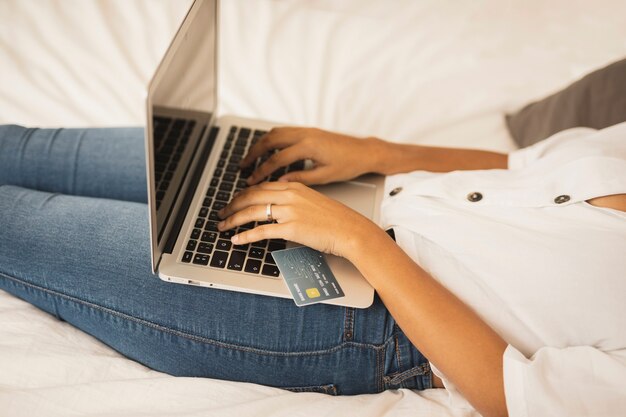 Mujer que trabaja en la computadora portátil de la cama