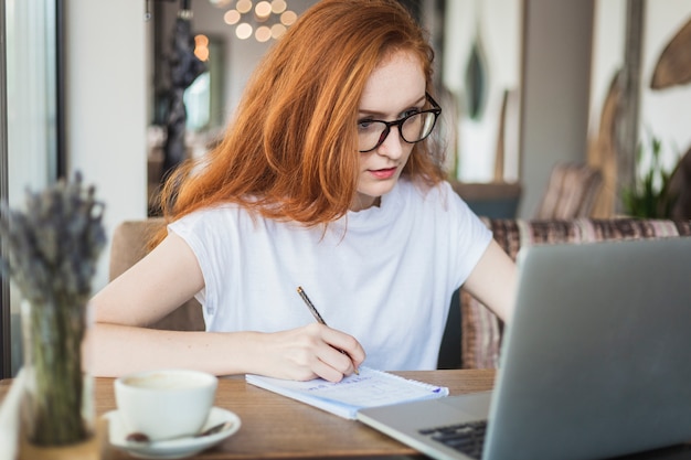 Foto gratuita mujer que trabaja en la computadora portátil en la mesa