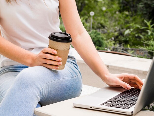 Mujer que trabaja en la computadora portátil mientras toma un café