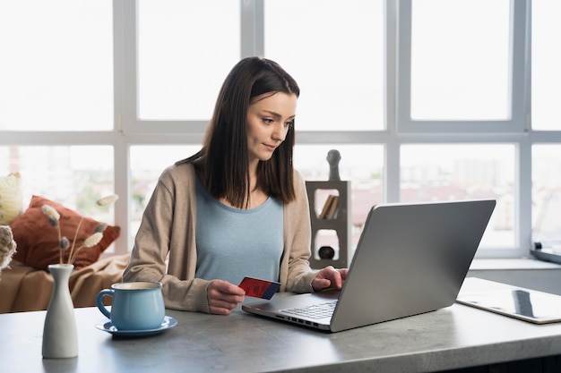 Mujer que trabaja en la computadora portátil con tarjeta de crédito