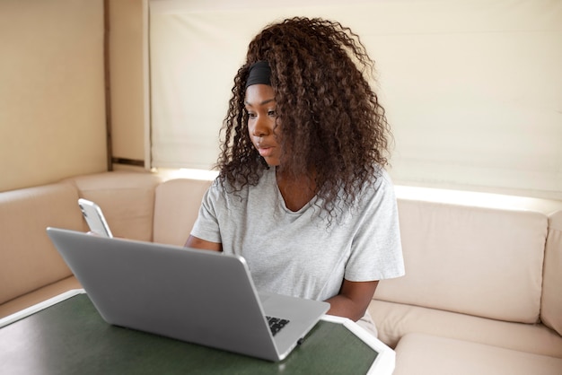 Foto gratuita mujer que trabaja en la computadora portátil de tiro medio