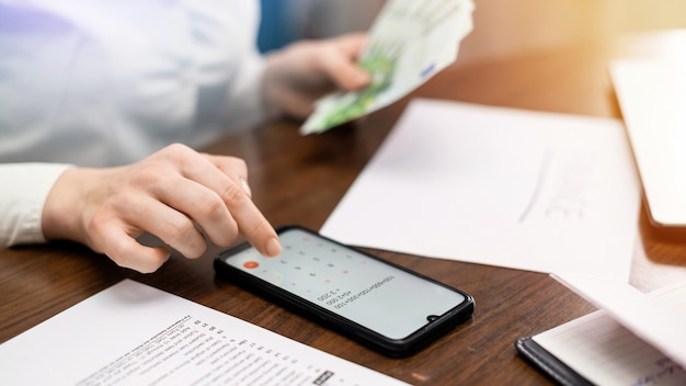 Mujer que trabaja con las finanzas sobre la mesa. Smartphone, dinero, bloc de notas