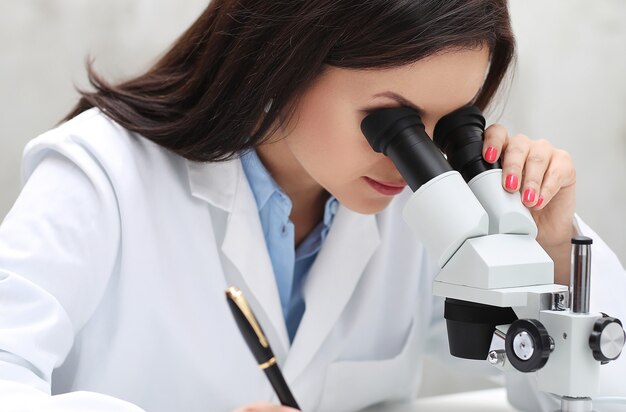 Mujer que trabaja en el laboratorio con un microscopio