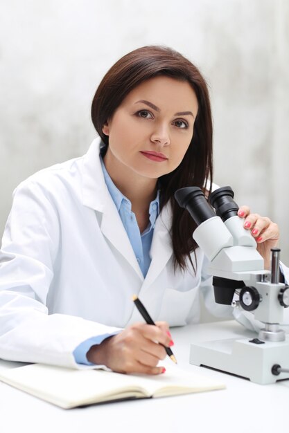 Mujer que trabaja en el laboratorio con un microscopio