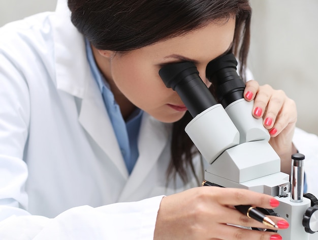 Mujer que trabaja en el laboratorio con un microscopio