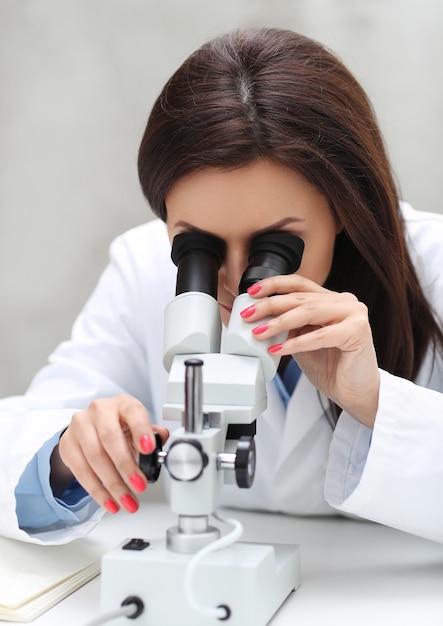 Mujer que trabaja en el laboratorio con un microscopio