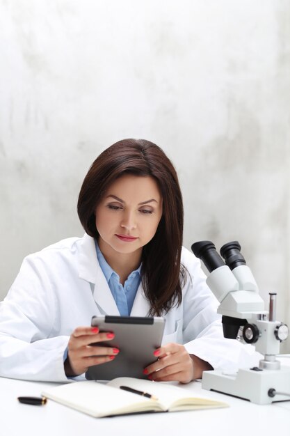 Mujer que trabaja en el laboratorio con un microscopio