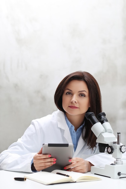 Mujer que trabaja en el laboratorio con un microscopio