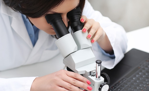Mujer que trabaja en el laboratorio con un microscopio