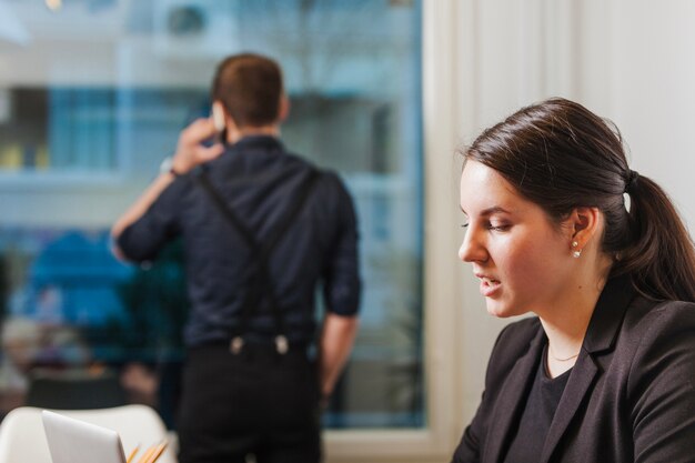 Mujer que trabaja mientras que el hombre que habla el teléfono