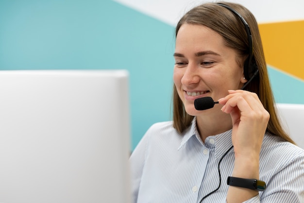 Mujer que trabaja en la oficina del centro de llamadas con auriculares y computadora