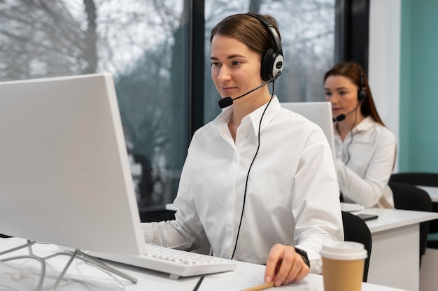 Mujer que trabaja en la oficina del centro de llamadas con auriculares y computadora