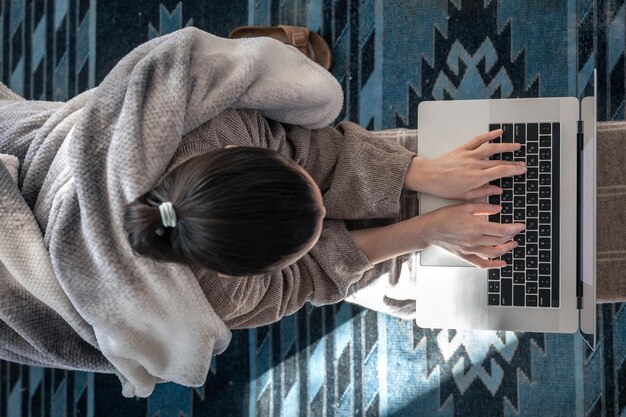 Una mujer que trabaja sentada en la vista superior de una computadora portátil