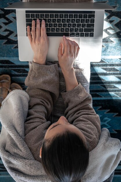 Una mujer que trabaja sentada en la vista superior de una computadora portátil