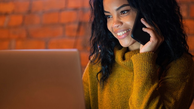 Foto gratuita mujer que trabaja en su computadora portátil mientras habla por teléfono