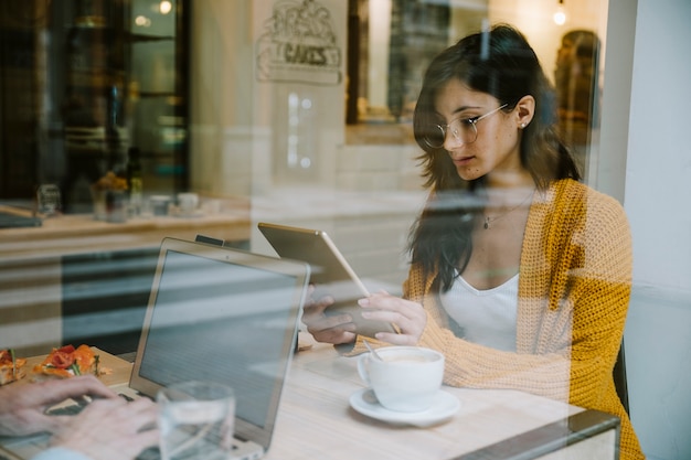 Foto gratuita mujer que trabaja con la tableta en la mesa de café