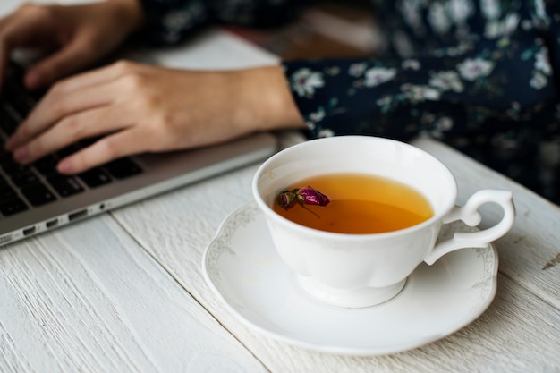Mujer que trabaja y una taza caliente de té floral