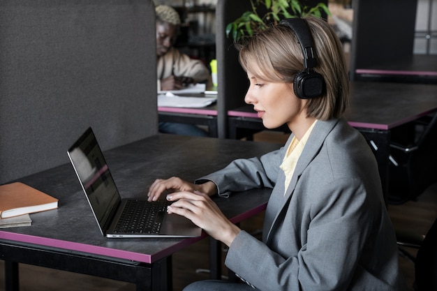 Mujer que trabaja en la vista lateral de la computadora portátil