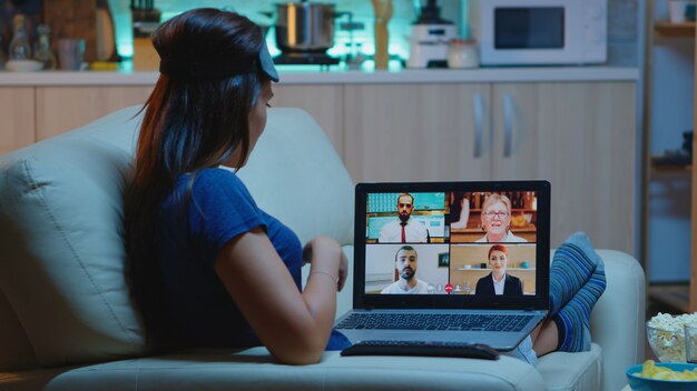 Mujer que transmite capacitación en seminarios web en línea por la noche desde su casa. Trabajador remoto que tiene reunión en línea, consulta por videoconferencia con colegas mediante videollamada y chat con cámara web que trabaja frente a la computadora portátil.