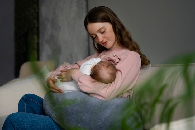 Foto gratuita mujer que usa almohada de lactancia en casa para un bebé recién nacido