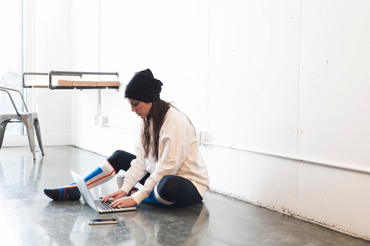 Foto gratuito mujer que usa la computadora portátil que se sienta en piso