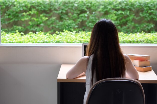 Mujer que usa la computadora portátil y el viejo libro de la vendimia