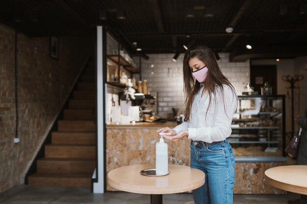 Mujer que usa gel desinfectante limpia las manos del virus coronavirus en el café.