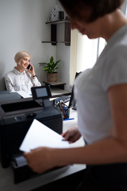 Foto gratuita mujer que usa la impresora en la oficina en el trabajo