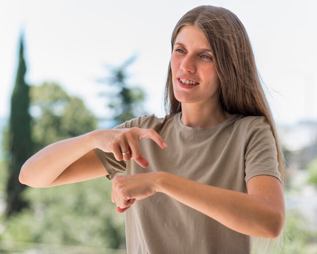 Mujer que usa el lenguaje de señas al aire libre para conversar