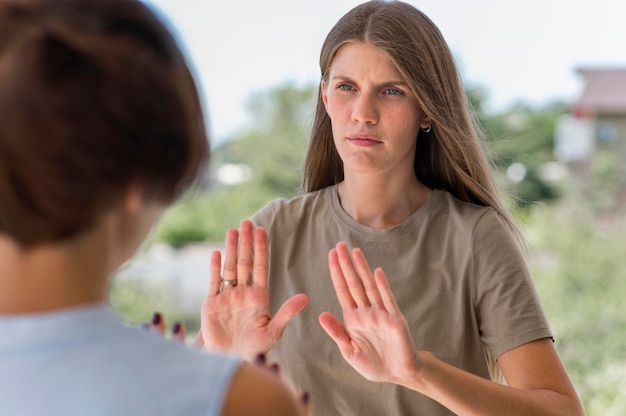 Mujer que usa el lenguaje de señas mientras está al aire libre para conversar con alguien