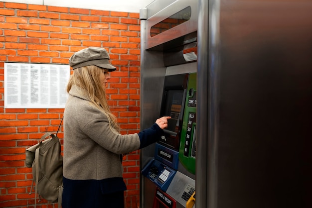 Mujer que usa una máquina de tarjetas de metro en la ciudad