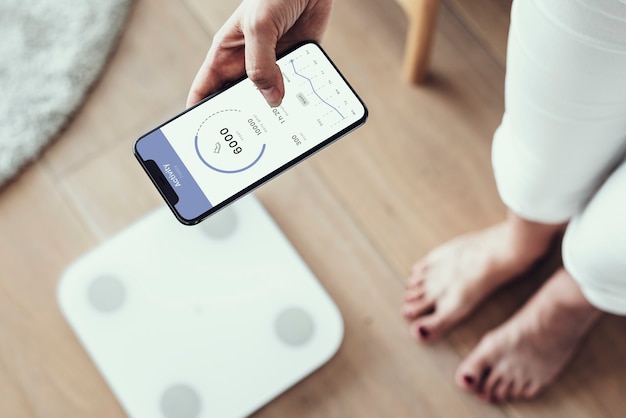 Mujer que usa el seguimiento de la salud en su teléfono mediante la tecnología innovadora de la báscula